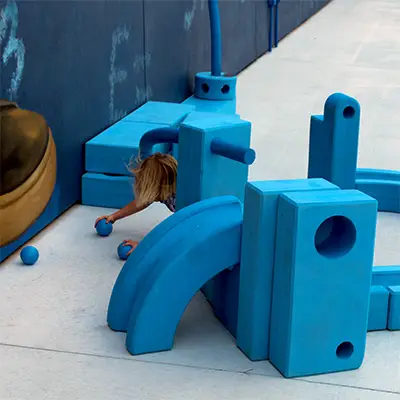 young boy playing outside the imagination station with giant, soft building blocks